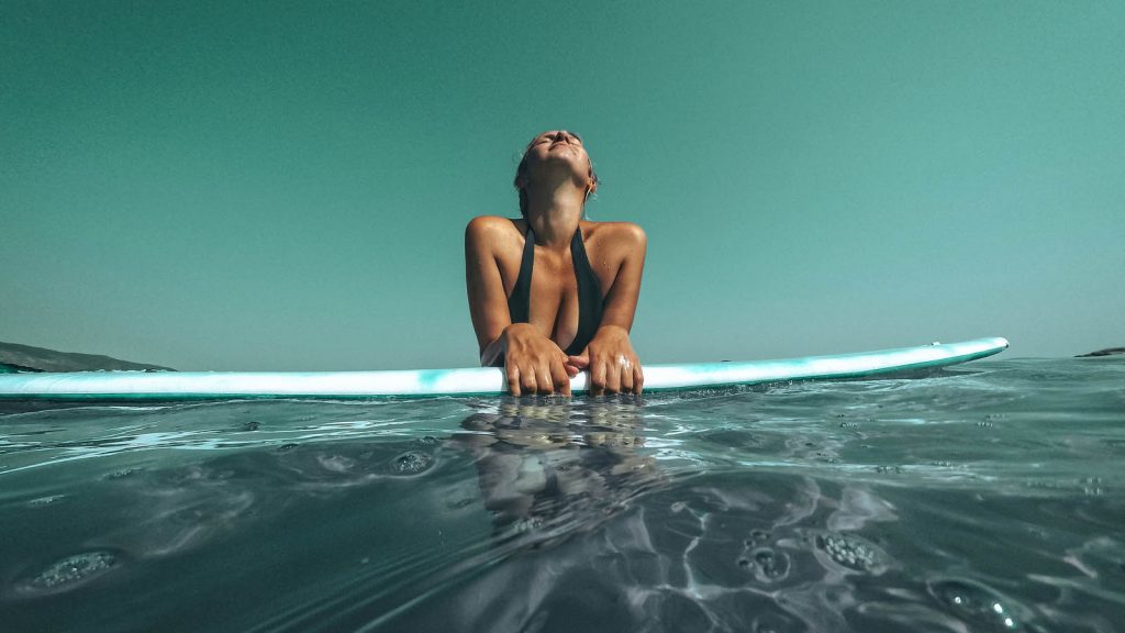 Photo of a young woman relaxing on a surfboard